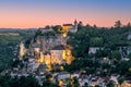 Majestic religious buildings of Rocamadour settlement lit with warm yellow illumination during twilight.ÃÂ Lot